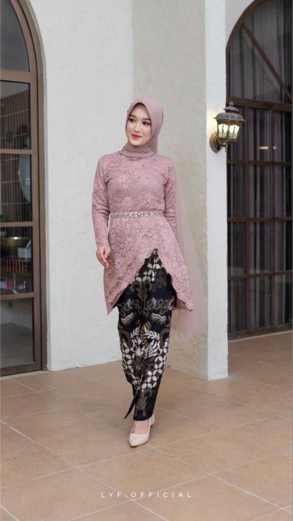Wanita memakai kebaya modern ungu muda dengan rok batik