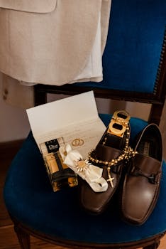 A stylish display of wedding accessories including shoes, invitations, and a rosary on a chair.