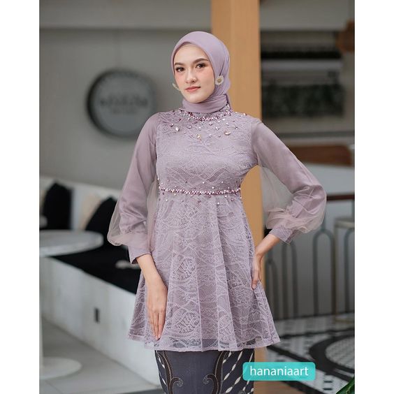 Wanita memakai kebaya brokat modern pastel ungu muda dengan hijab dan detail payet