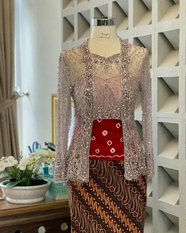 Kebaya brokat modern lengan panjang abu-abu dengan aksen bordir merah, dipadukan dengan kain batik