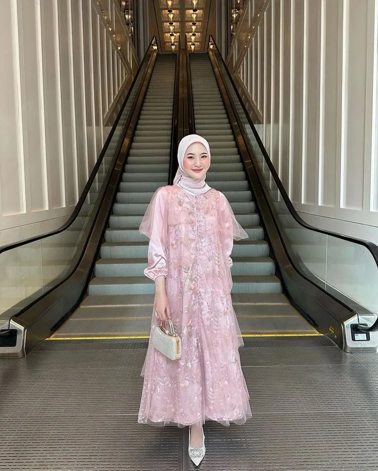Wanita memakai kebaya hijab modern brokat pink muda di tangga
