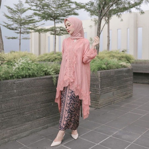 Wanita memakai kebaya modern pink dengan rok batik